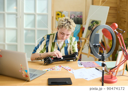 Young female with physical impairment putting small stickers on her prosthesis Young female with physical impairment putting small stickers on her prosthesis 90474172