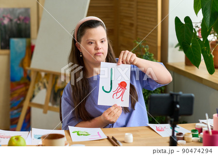 Girl showing paper with English letter and drawing of jellyfish to audience Girl showing paper with English letter and drawing of jellyfish to audience 90474294