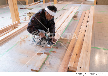 木造住宅の現場で電動ノコギリと曲尺で木材の加工をする大工 木造住宅の現場で電動ノコギリと曲尺で木材の加工をする大工 90475930