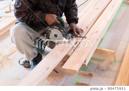 木造住宅の現場で電動ノコギリと曲尺で木材の加工をする大工 木造住宅の現場で電動ノコギリと曲尺で木材の加工をする大工 90475931
