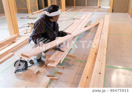 木造住宅の現場で電動ノコギリと曲尺で木材の加工をする大工 木造住宅の現場で電動ノコギリと曲尺で木材の加工をする大工 90475933