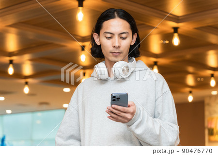 スマホを持つヘッドフォンの男性 90476770