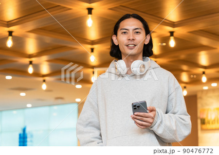 スマホを持つヘッドフォンの男性 90476772