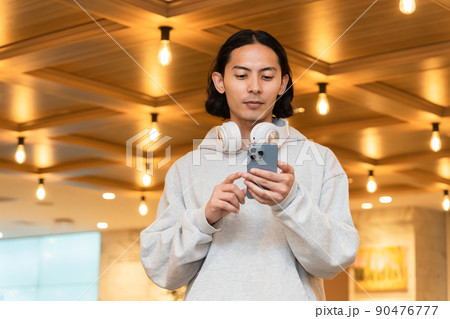 スマホを持つヘッドフォンの男性 スマホを持つヘッドフォンの男性 90476777