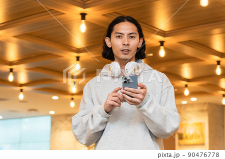 スマホを持つヘッドフォンの男性 90476778