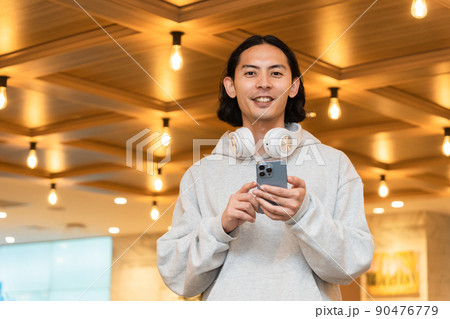 スマホを持つヘッドフォンの男性 スマホを持つヘッドフォンの男性 90476779