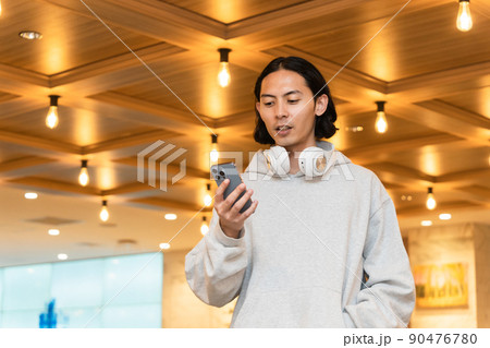 スマホを持つヘッドフォンの男性 スマホを持つヘッドフォンの男性 90476780