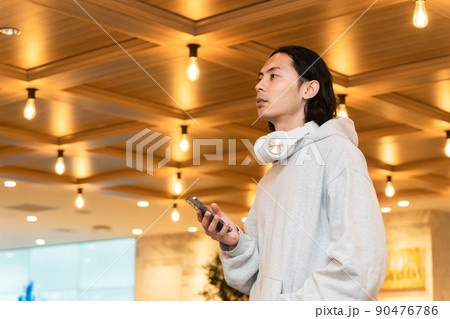 スマホを持つヘッドフォンの男性 スマホを持つヘッドフォンの男性 90476786