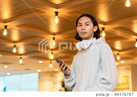 スマホを持つヘッドフォンの男性 90476787