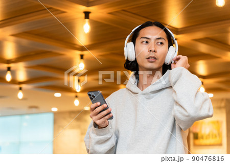 スマホを持つヘッドフォンの男性 スマホを持つヘッドフォンの男性 90476816
