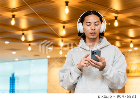 スマホを持つヘッドフォンの男性 スマホを持つヘッドフォンの男性 90476831