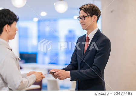 名刺交換をするエンジニアとビジネスマン 90477498