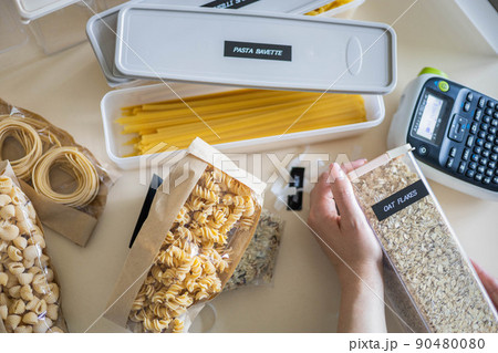 Closeup female hands applying printing sticker with oat flakes title on transparent plastic case Closeup female hands applying printing sticker with oat flakes title on transparent plastic case 90480080