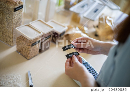 Top view female hands creating names title stickers for food comfortable storage use labeler machine 90480086