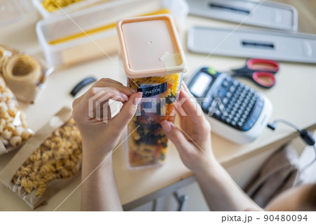 Closeup female hands sticking label on plastic package pasta. Storage organization of food products 90480094