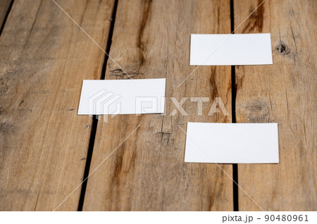 Three Blank business cards against a wooden background. White paper rectangles lie on top of old cracked boards. Selective focus. Three Blank business cards against a wooden background. White paper rectangles lie on top of old cracked boards. Selective focus. 90480961