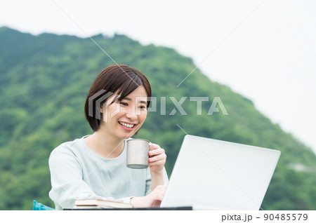 屋外でコーヒーを飲みながらパソコンを見る女性 屋外でコーヒーを飲みながらパソコンを見る女性 90485579