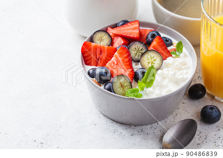 Cottage cheese with strawberries, nuts and blueberries in gray bowl for breakfast. Summer recipe. Cottage cheese with strawberries, nuts and blueberries in gray bowl for breakfast. Summer recipe. 90486839