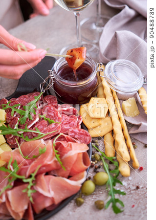 woman dips parmesan cheese into sauce, Two glasses of white wine and Italian antipasto meat platter 90488789
