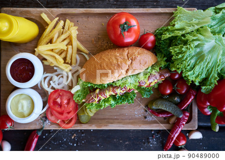 BBQ hot dog served with vegetables and French fries and sauces on wooden serving board 90489000