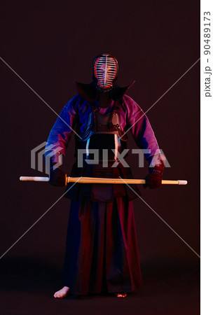 Close up shot, Kendo fighter wearing in an armor, traditional kimono, helmet practicing martial art with shinai bamboo sword, black background. Close up shot, Kendo fighter wearing in an armor, traditional kimono, helmet practicing martial art with shinai bamboo sword, black background. 90489173