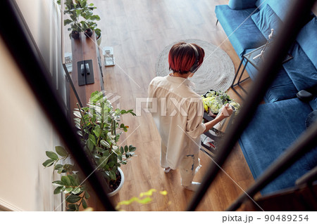 Guy in headphones watering green house plant at home Guy in headphones watering green house plant at home 90489254