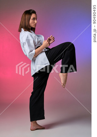 Athletic woman in traditional kimono is practicing karate in studio. 90490495