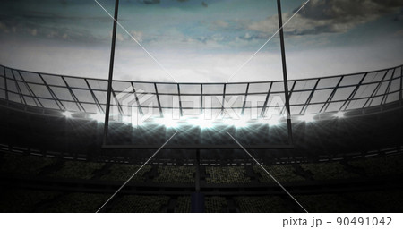 Image of american football goalposts and cloudy sky at floodlit stadium 90491042
