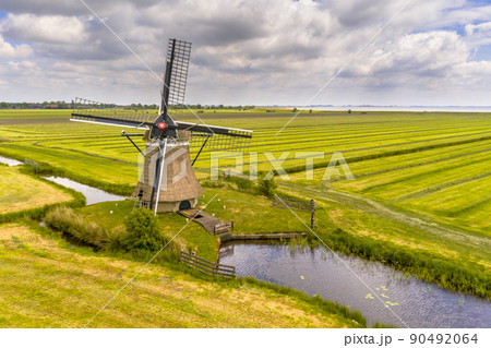 Old wooden windmill in green agricultural grassland 90492064