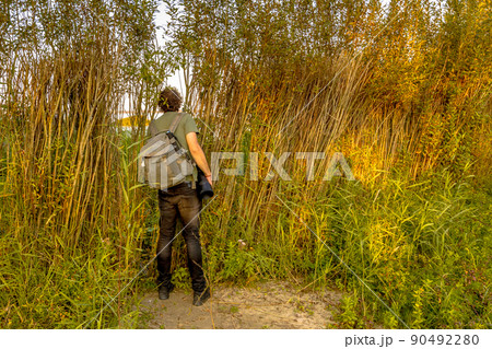 Nature photographer peeking through natural hide 90492280