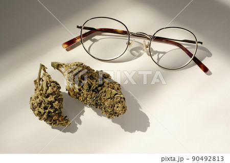 Ophthalmology and cannabis concept. Marijuana buds with glasses on beige background. Alternative Glaucoma Therapies Ophthalmology and cannabis concept. Marijuana buds with glasses on beige background. Alternative Glaucoma Therapies 90492813
