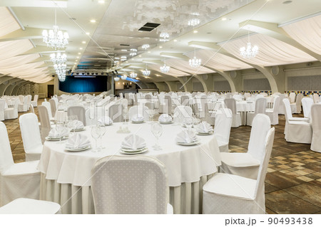 Elegant banquet hall interior prepared for feast with served tables and stage 90493438