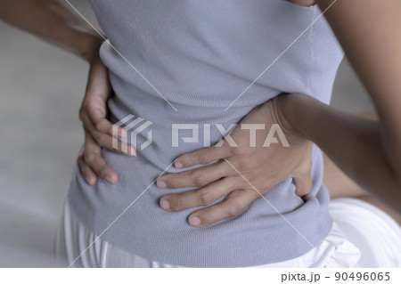 Adult female is holding her lower back and suffering from chronic back pain 90496065