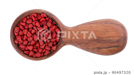Annatto seeds in wooden spoon, isolated on a white background. Achiote seeds, bixa orellana. Natural dye for cooking and food. Close-up. Top view. 90497320