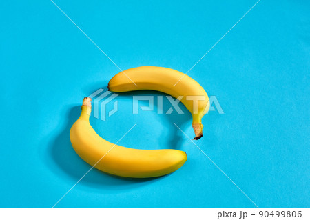 Two yellow ripe bananas on blue background with space for text or design. Top view Two yellow ripe bananas on blue background with space for text or design. Top view 90499806