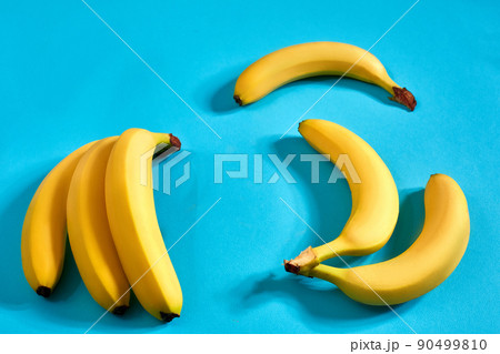 Yellow ripe bananas on blue background with space for text or design. Top view Yellow ripe bananas on blue background with space for text or design. Top view 90499810