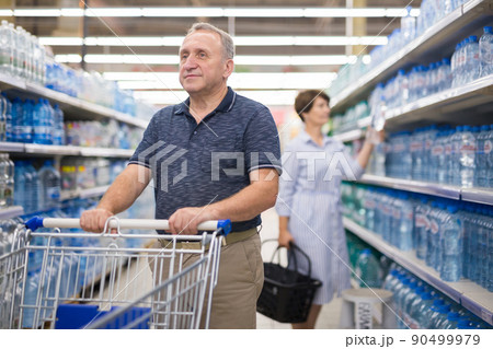 A mature man examines a bottle of drinking water 90499979