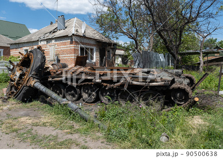 A burnt Russian tank near a residential building. War in Ukraine 2022. Russian missiles in Kharkiv countryside Ukraine. Russian aggression. Russian attack on Ukraine.  90500638