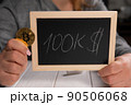 A woman holding a board with the inscription 100 thousand dollars and a bitcoin. 90506068