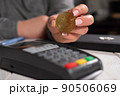 Close-up woman holding golden bitcoin coin near terminal for payment. 90506069
