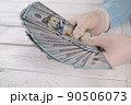 Close-up of a woman in gloves holding a stack of one hundred dollar bills. 90506073