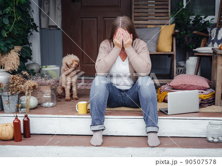 middle aged depressed woman sitting on porch. 90507578