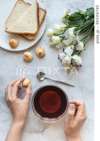 Top view of a woman's hands with a cup of tea, cookies, toasted bread, flowers Top view of a woman's hands with a cup of tea, cookies, toasted bread, flowers 90509795