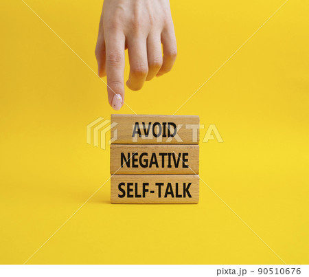 Avoid negative self-talk symbol. Concept words Avoid negative self-talk on wooden blocks. Beautiful yellow background. Bisinessman hand. Business and Avoid negative self-talk concept. Copy space. 90510676