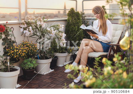 Woman Reading Book on Green Terrace 90510684