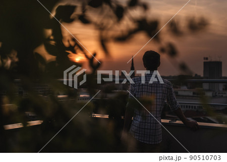 Man Watching Sunset on Rooftop Garden 90510703