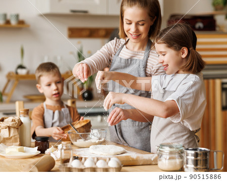Happy woman and cute children cooking together in kitchen Happy woman and cute children cooking together in kitchen 90515886