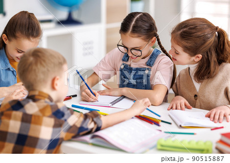 Diligent schoolkids solving test with classmates at school in daytime Diligent schoolkids solving test with classmates at school in daytime 90515887