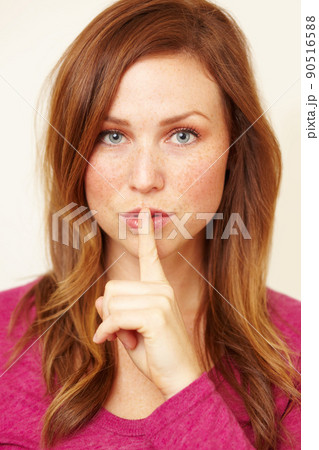 Ssh..you didnt hear it from me. Portrait of a beautiful young woman with her finger to her lips. Ssh..you didnt hear it from me. Portrait of a beautiful young woman with her finger to her lips. 90516588