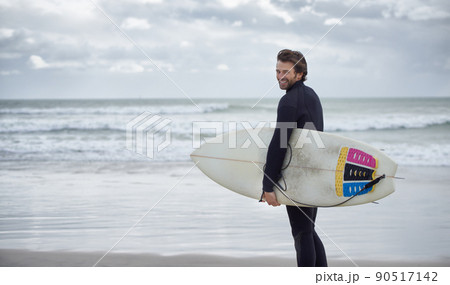 Hitting the beach. A surfer with his surfboard at the beach. 90517142